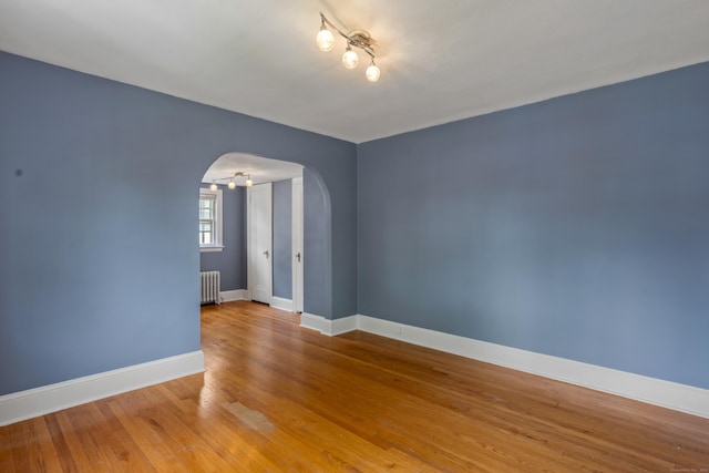 25 S Highland St, West Hartford, CT 06119 - unfurnished room with arched walkways, radiator heating unit, baseboards, wood finished floors, and rail lighting