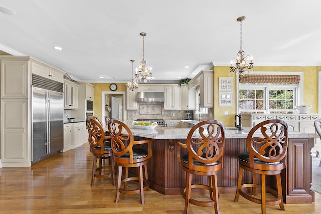 22 Nature Ln, Shelton, CT 06484 - kitchen featuring built in appliances, a chandelier, under cabinet range hood, cream cabinetry, and crown molding
