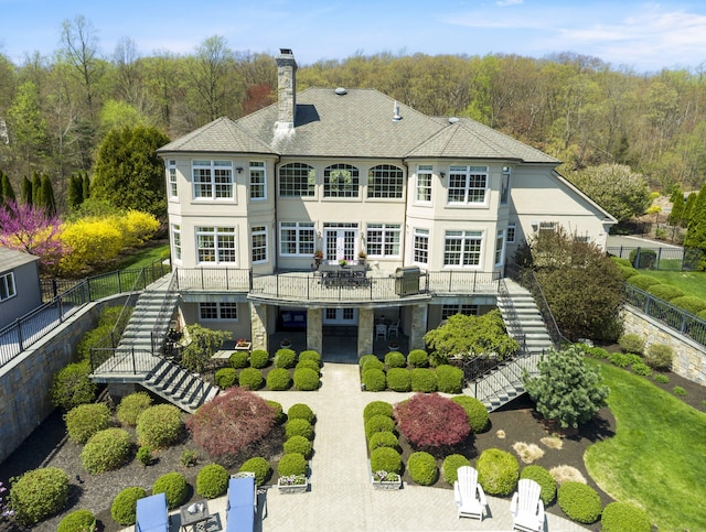 22 Nature Ln, Shelton, CT 06484 - back of house featuring stairway, a chimney, stucco siding, and a wooded view