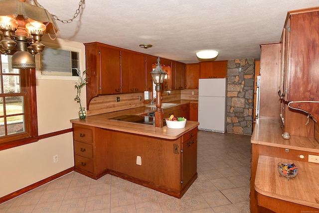 88 Milwood Rd, East Hartford, CT 06118 - kitchen with light floors, freestanding refrigerator, black electric stovetop, a peninsula, and brown cabinetry