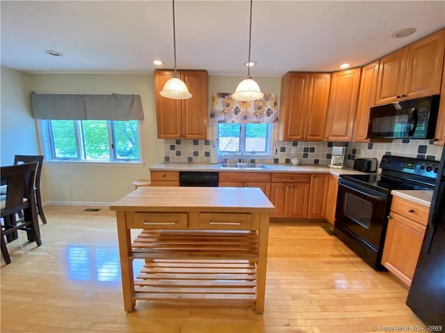 kitchen featuring light countertops, a wealth of natural light, a sink, and black appliances