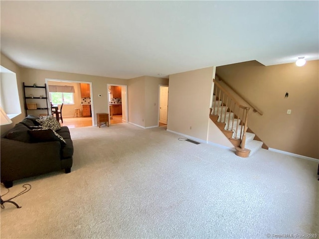 living area featuring stairway, baseboards, and light carpet