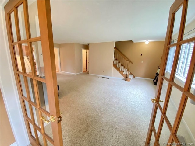 unfurnished living room with light carpet, french doors, visible vents, baseboards, and stairway