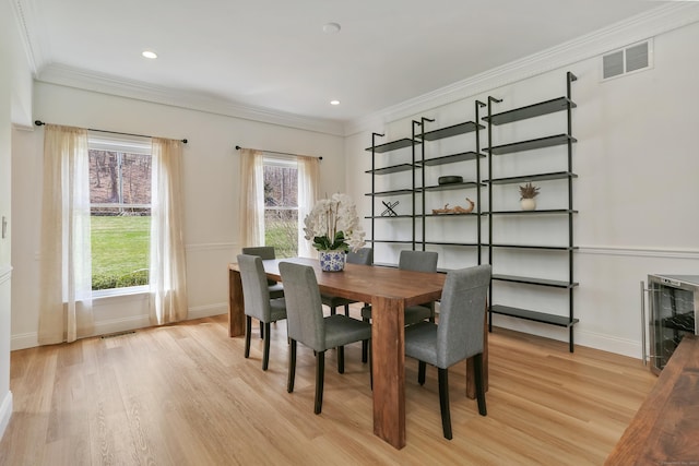 dining area with light wood-style floors, visible vents, crown molding, and baseboards