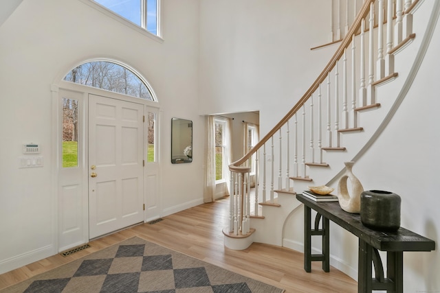 entryway featuring visible vents, baseboards, wood finished floors, and a high ceiling