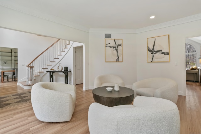 living room featuring baseboards, visible vents, light wood-style floors, stairs, and crown molding