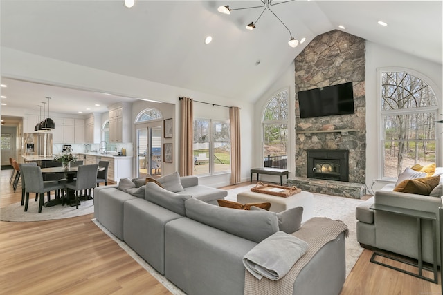 living area featuring a fireplace, light wood-type flooring, high vaulted ceiling, and recessed lighting