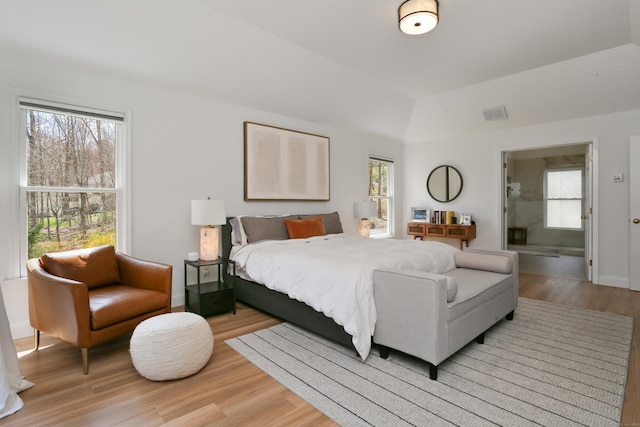 bedroom with light wood-style floors, vaulted ceiling, visible vents, and baseboards