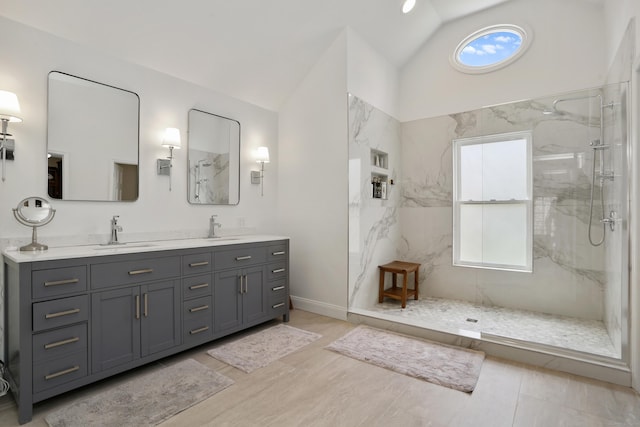 full bathroom featuring vaulted ceiling, a marble finish shower, a sink, and double vanity