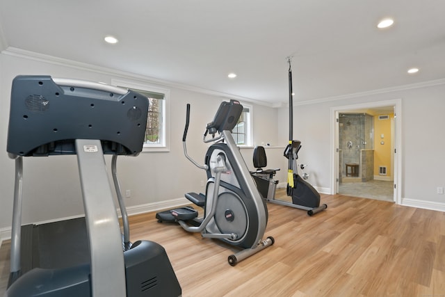 exercise area featuring visible vents, baseboards, wood finished floors, and ornamental molding