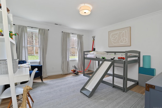 bedroom featuring multiple windows, ornamental molding, wood finished floors, and visible vents