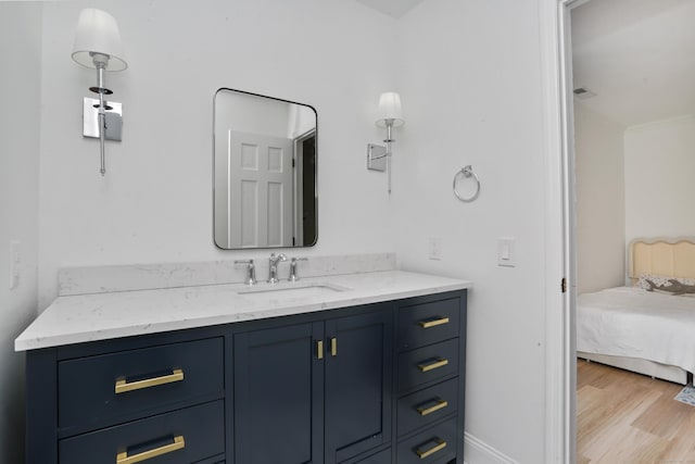 bathroom with ensuite bath, vanity, and wood finished floors