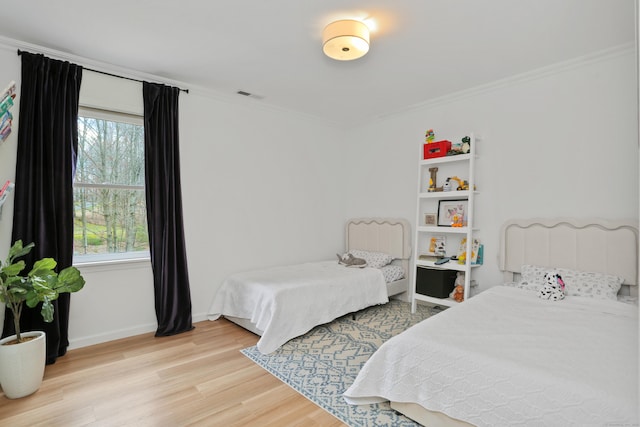 bedroom featuring visible vents, light wood-style floors, ornamental molding, and multiple windows