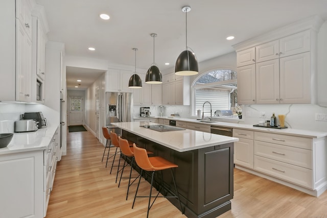 kitchen featuring stainless steel appliances, a breakfast bar, a center island, light wood-style flooring, and white cabinetry