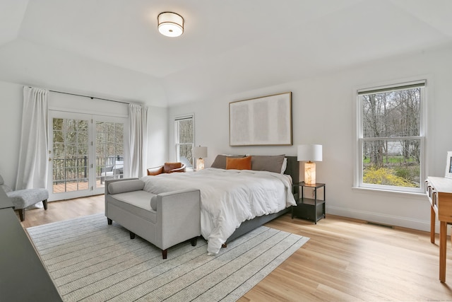 bedroom featuring vaulted ceiling, multiple windows, access to exterior, and light wood-type flooring