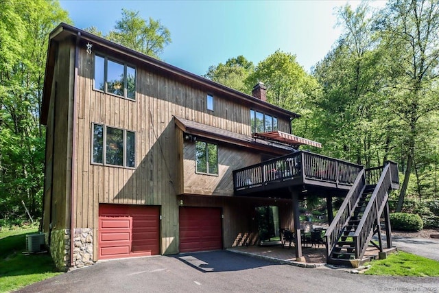 view of front of property with a garage, a chimney, driveway, a wooden deck, and stairway