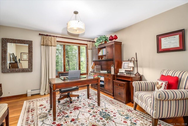 home office featuring a baseboard heating unit, light wood-style floors, and baseboards