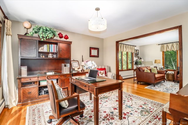 office space with light wood-type flooring, a baseboard radiator, and baseboard heating