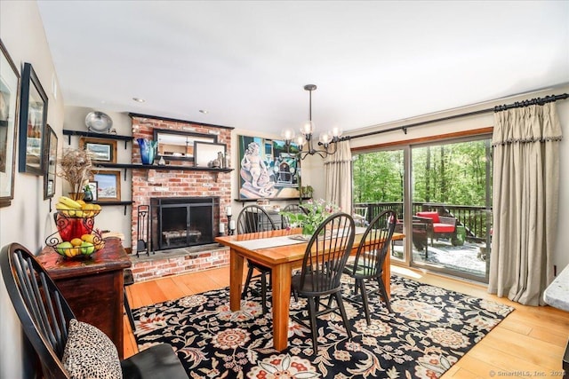 dining space with hardwood / wood-style flooring, a brick fireplace, and a chandelier