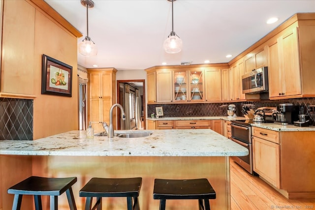 kitchen featuring appliances with stainless steel finishes, a sink, tasteful backsplash, a breakfast bar, and recessed lighting