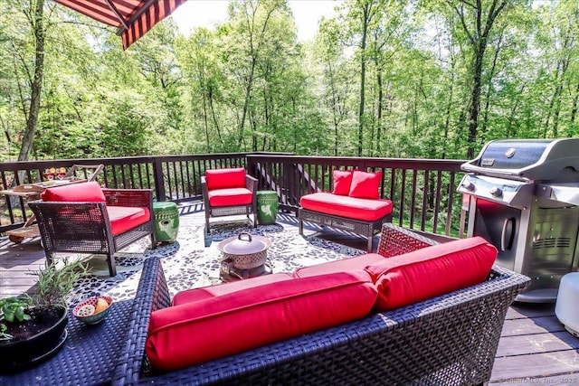 wooden deck featuring an outdoor living space, a grill, and a forest view