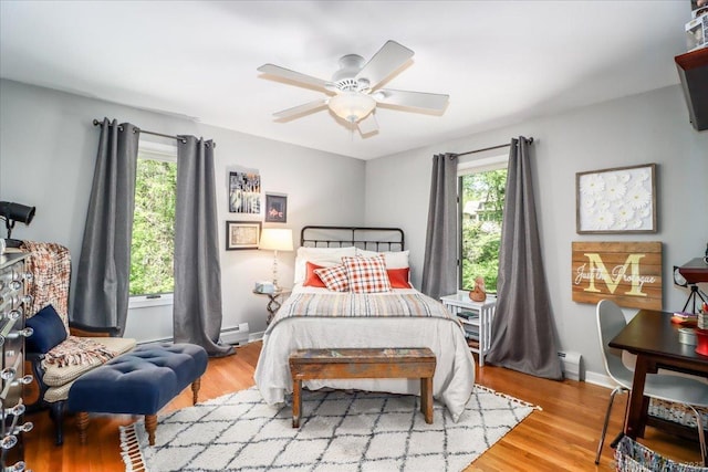bedroom featuring multiple windows, a baseboard radiator, and wood finished floors