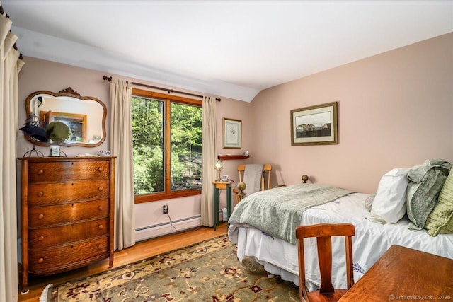 bedroom with a baseboard heating unit and wood finished floors