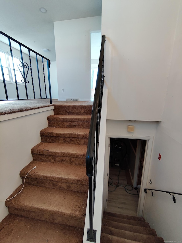 stairs with wood finished floors and visible vents