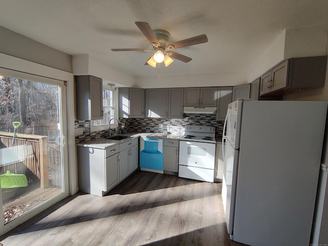 kitchen featuring backsplash, a ceiling fan, gray cabinets, a sink, and white appliances