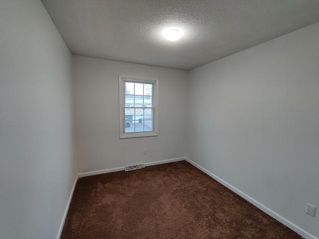 unfurnished room with baseboards, dark colored carpet, a textured ceiling, and visible vents
