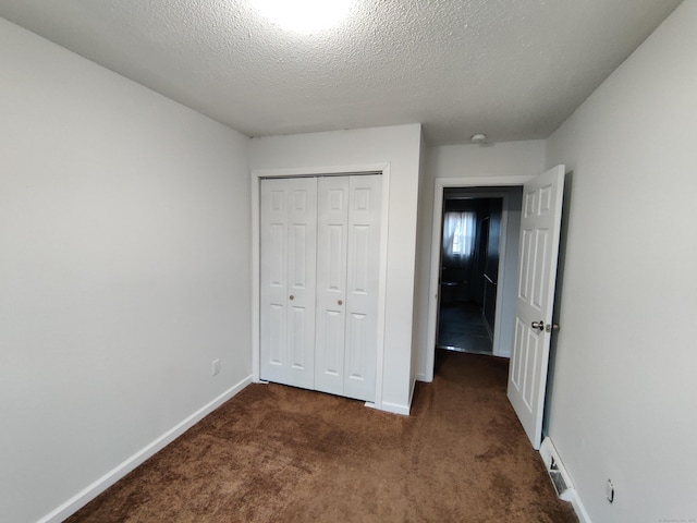 unfurnished bedroom with a textured ceiling, baseboards, carpet floors, and a closet
