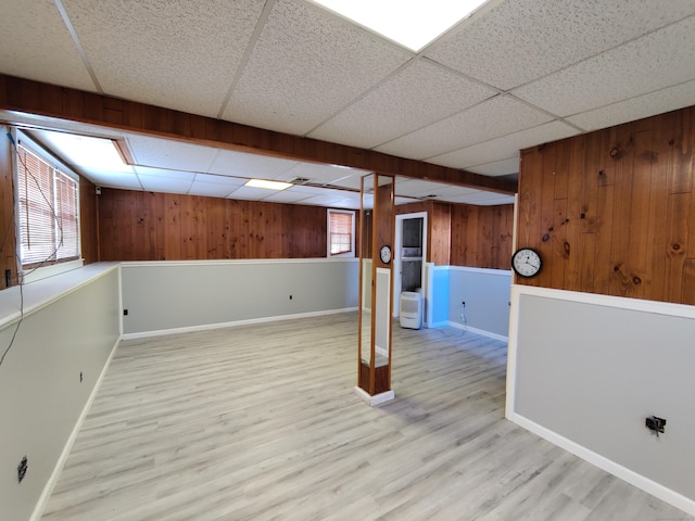 below grade area featuring wood walls, wood finished floors, a paneled ceiling, and baseboards