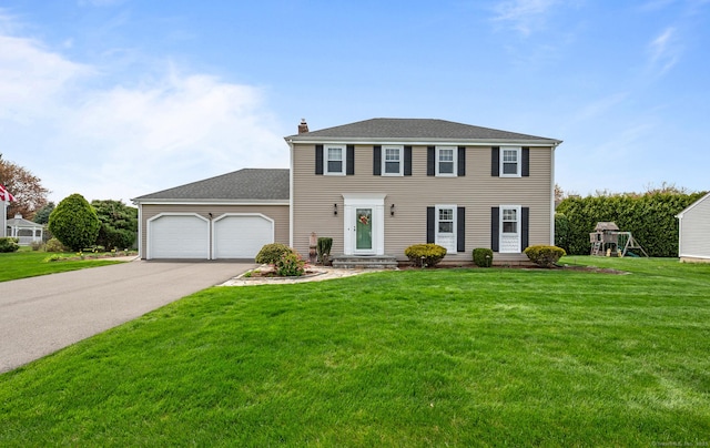 colonial inspired home featuring roof with shingles, a front lawn, a garage, a chimney, and driveway