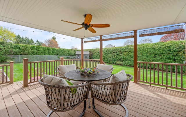 wooden deck with outdoor dining area, a yard, a ceiling fan, a storage shed, and an outbuilding