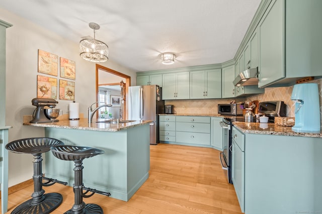 kitchen featuring appliances with stainless steel finishes, range hood, light stone countertops, tasteful backsplash, and light wood-type flooring