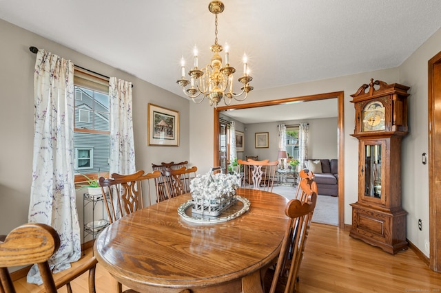dining area with baseboards, light wood-style flooring, a chandelier, and a healthy amount of sunlight