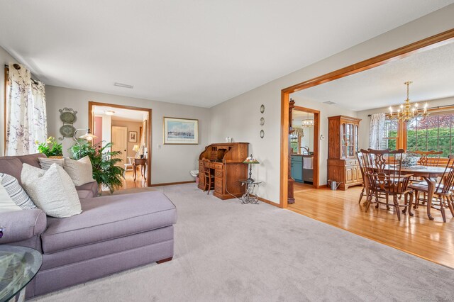 carpeted living room with baseboards, a chandelier, and visible vents
