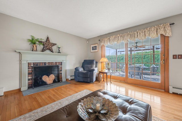 living area with wood-type flooring, a baseboard heating unit, and a fireplace