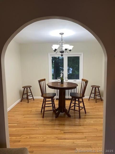 12 Homecrest St, Newington, CT 06111 - dining area with arched walkways, a chandelier, light wood-style flooring, and baseboards