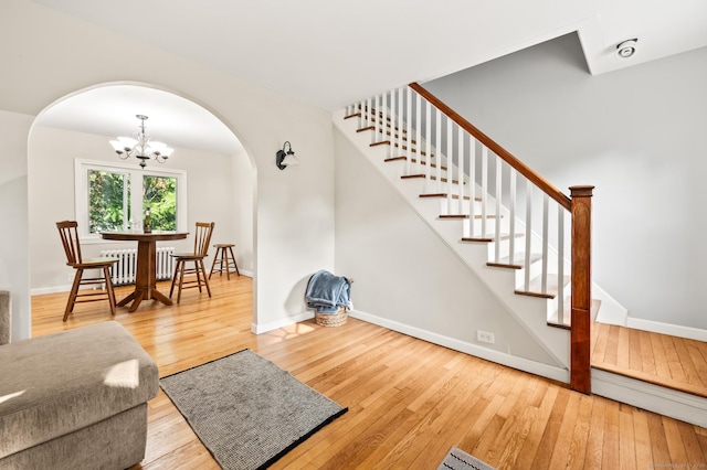 12 Homecrest St, Newington, CT 06111 - living area featuring radiator heating unit, arched walkways, hardwood / wood-style flooring, and a chandelier