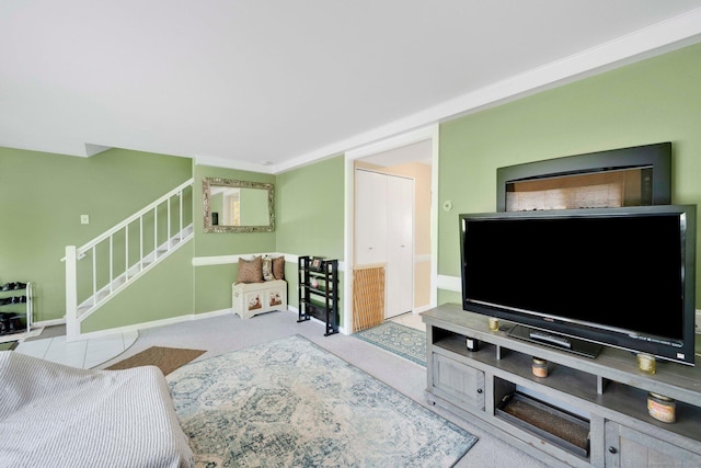 carpeted living area featuring baseboards and stairs