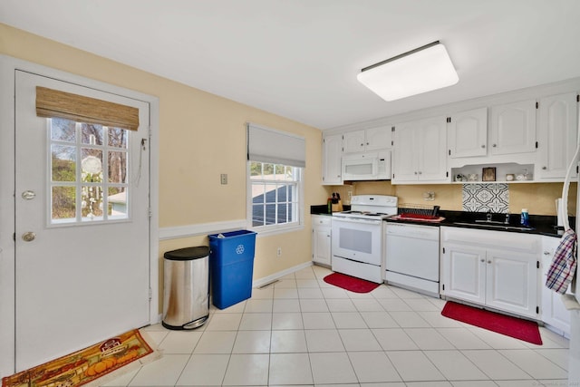 kitchen with visible vents, dark countertops, a sink, white appliances, and white cabinetry