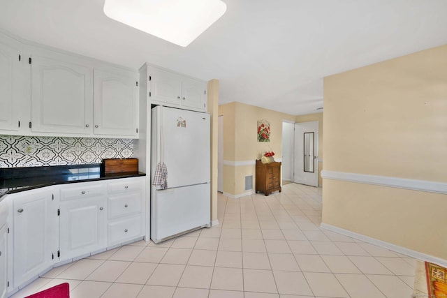 kitchen with baseboards, freestanding refrigerator, white cabinets, and dark countertops