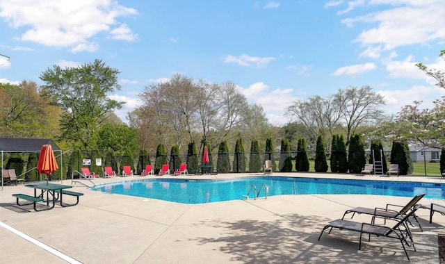 pool with a patio area and fence