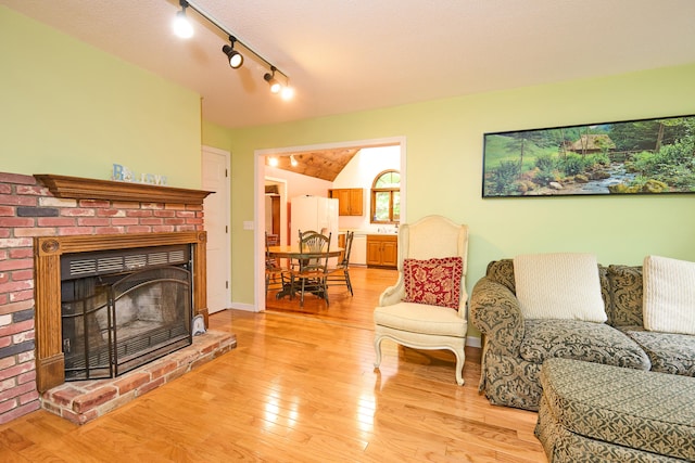 581 Oxford Rd, Oxford, CT 06478 - living room with light wood-style flooring, a fireplace, vaulted ceiling, rail lighting, and baseboards