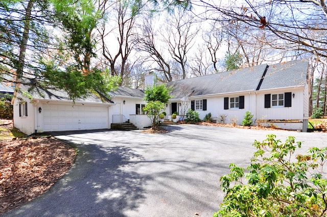 ranch-style home featuring a chimney and aphalt driveway