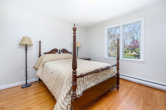 bedroom with baseboards, light wood-style floors, and a baseboard radiator