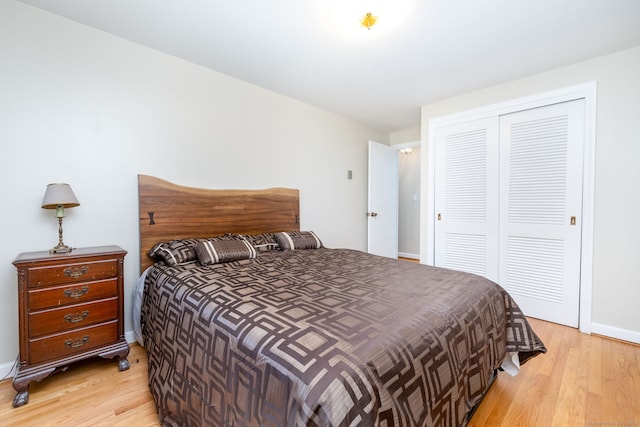 bedroom with baseboards, a closet, and light wood-style flooring
