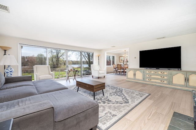 living room featuring visible vents, light wood-type flooring, and a chandelier