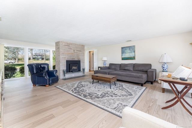 living area featuring a fireplace, visible vents, and light wood-style flooring